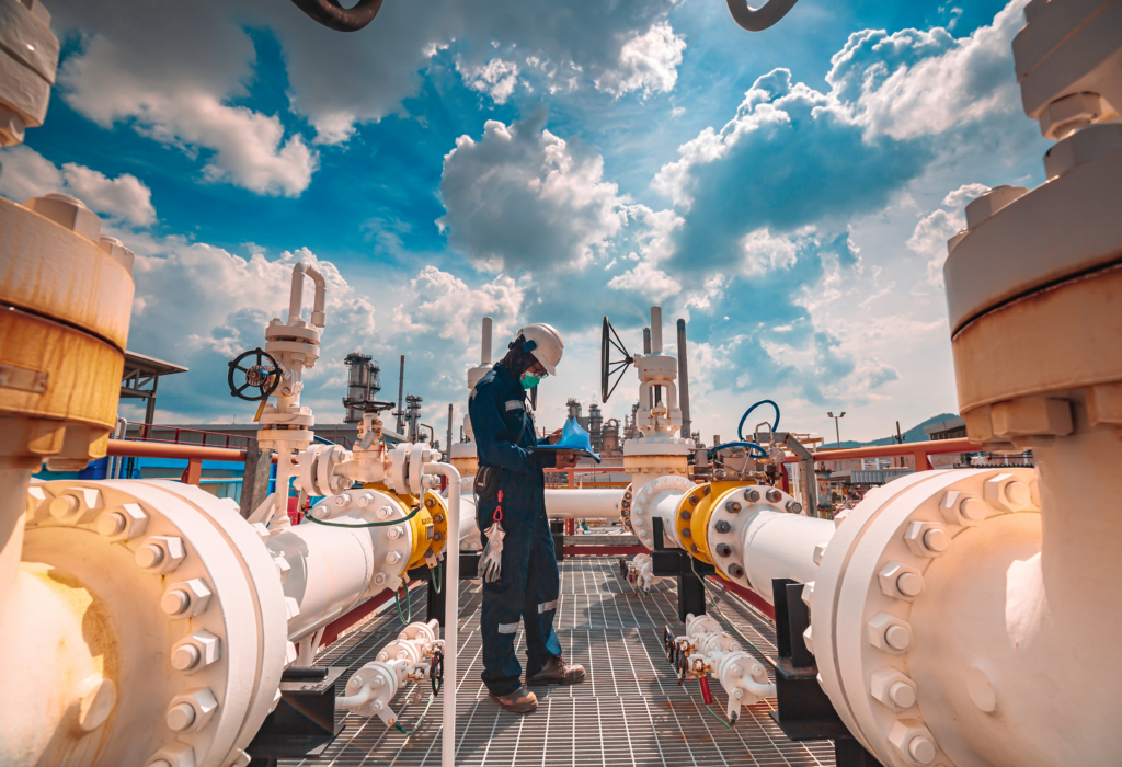Oilfield worker standing amongst refinery piping.